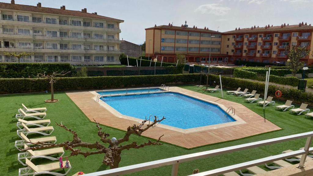 a swimming pool in a yard with chairs and a building at FESTASTAR ESTARTIT PLAYA in L'Estartit