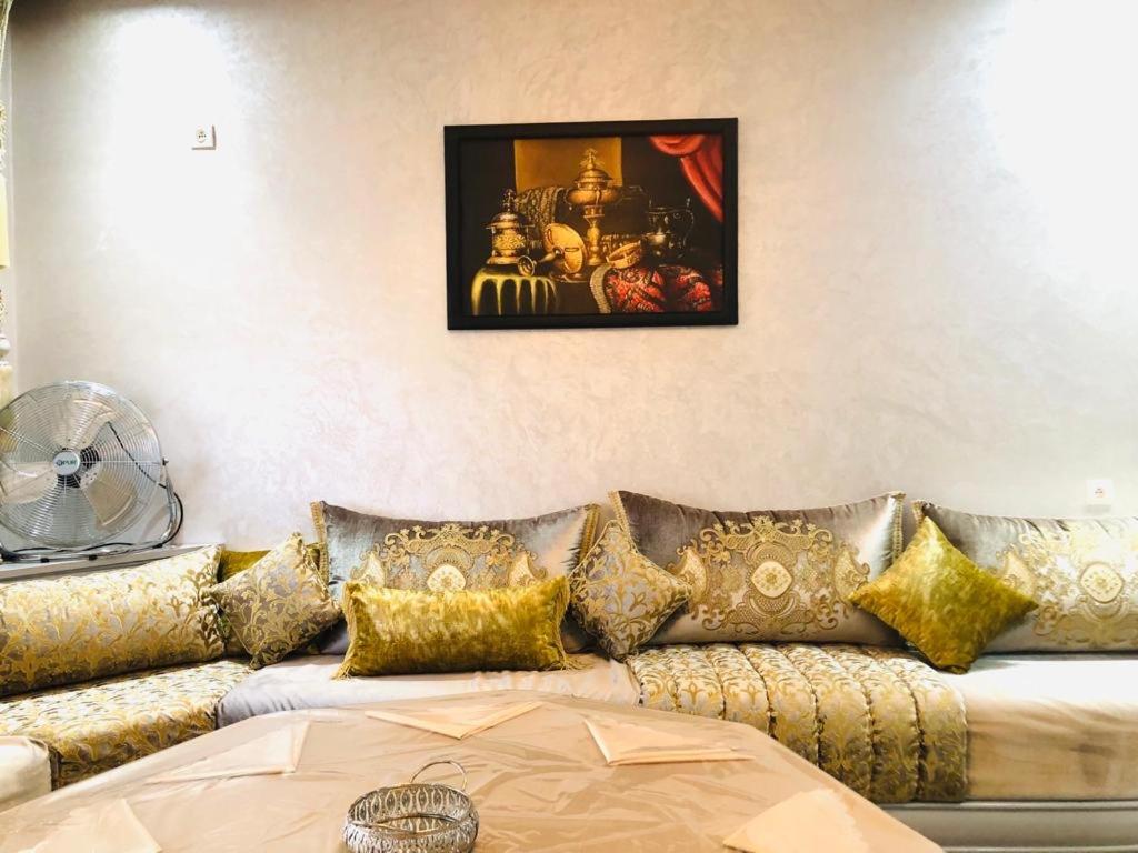 een woonkamer met een bank met gouden kussens bij L impérial appart haut founty in Agadir
