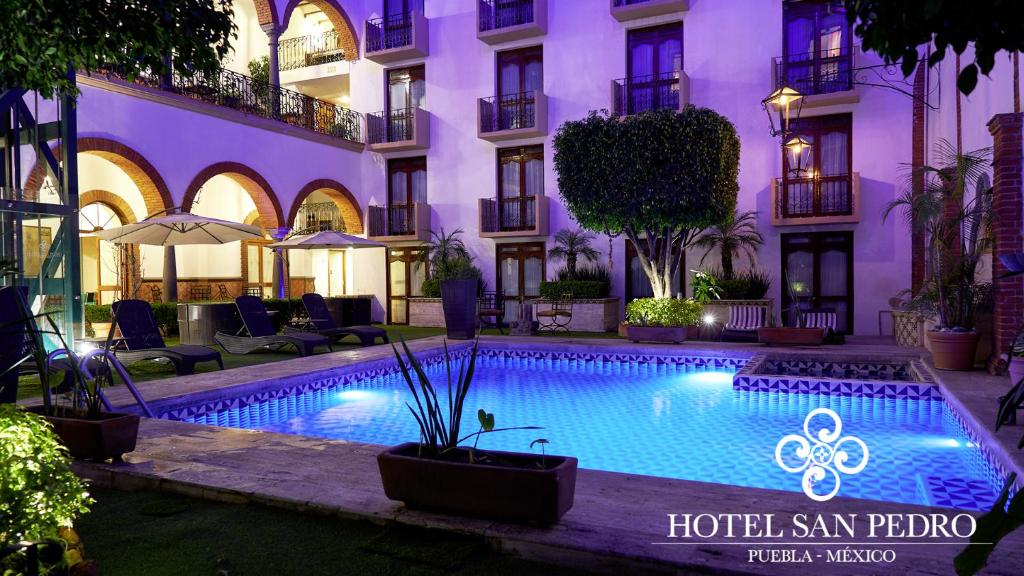 a hotel with a swimming pool in front of a building at Hotel San Pedro Puebla in Puebla