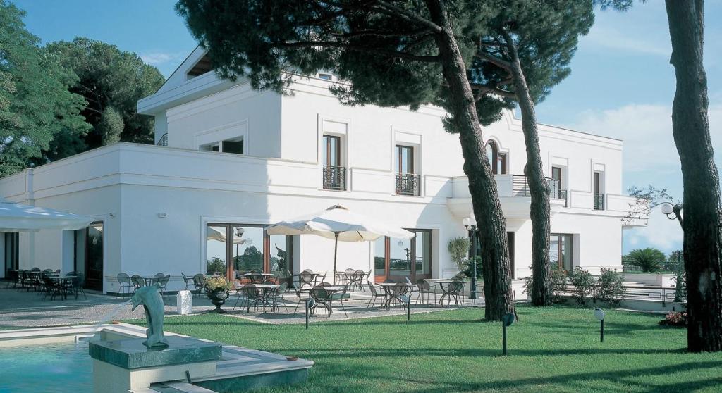 a white house with a statue in front of it at LH Hotel Domus Caesari in Marino