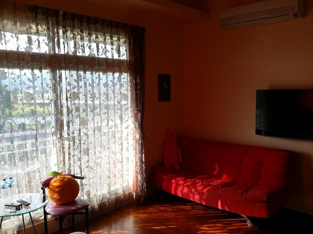 a living room with a red couch and a window at Jing Xiang Hua Nong B&amp;B in Dongshan