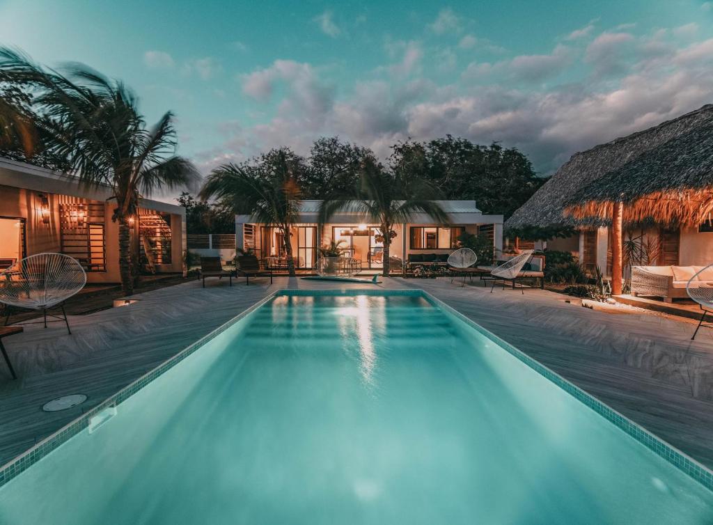 uma piscina com uma villa ao fundo em El Pez Surf Hotel em Popoyo