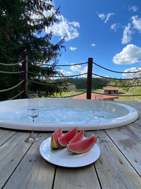a plate of watermelon on a table with wine glasses at Góra Jabłek Mazury Mikolajki in Lipowo