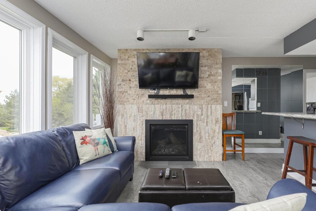Una sala de estar con un sofá azul y una chimenea. en Condo at Blue Mountain on Ski Run Close to Village, en Blue Mountains