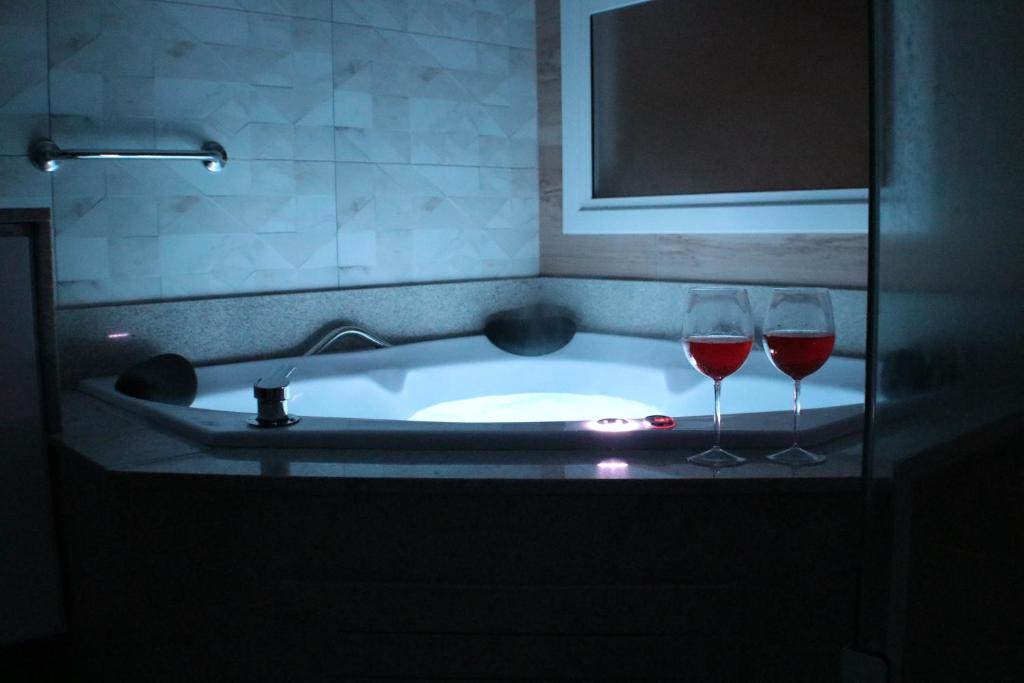 Dois copos de vinho ao lado de uma banheira em DUPLEX COM JACUZZI NA BORGES - SATTVA HOME em Gramado