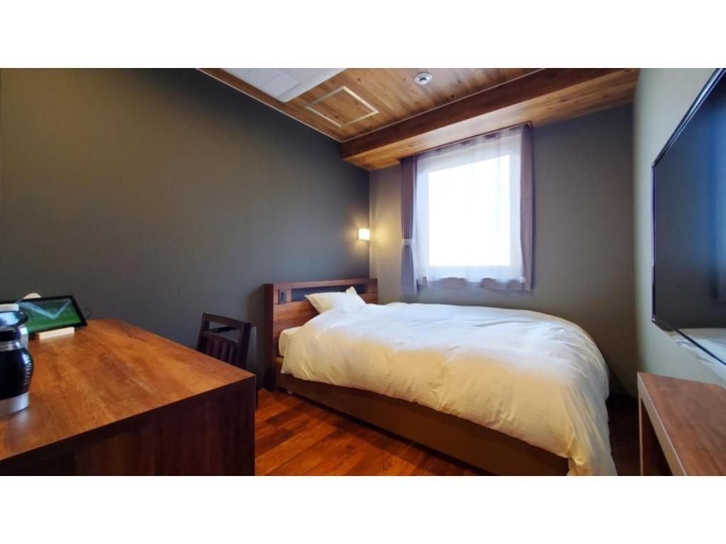 um quarto com uma cama, uma secretária e uma televisão em ｂｕｓｉｎｅｓｓ&ａｃｔｉｖｉｔｙ ｃｈａｎｖｒｅ - Vacation STAY 64302v em Tochigi