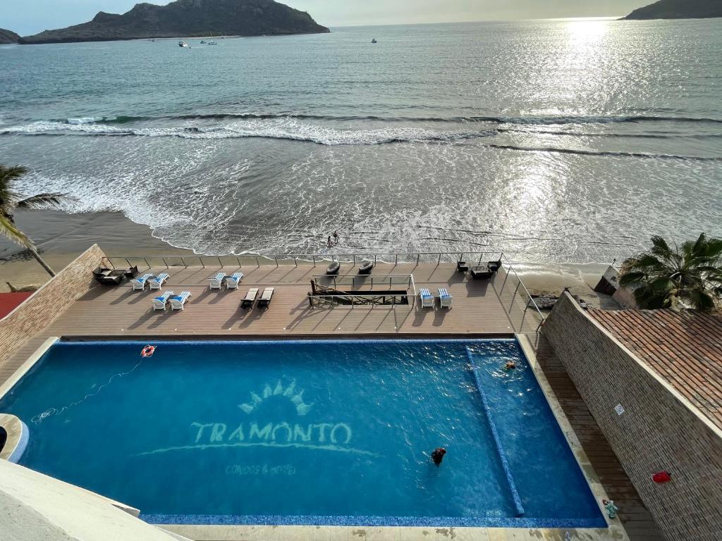 a swimming pool next to a beach with the ocean at Tramonto Resort Mazatlan in Mazatlán