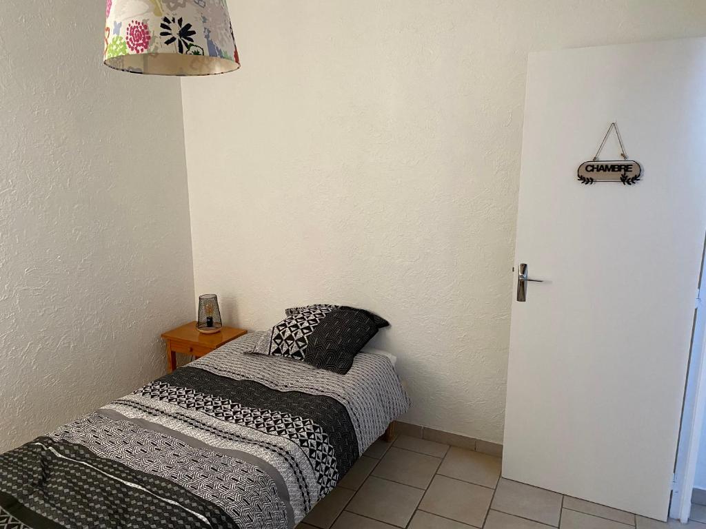a small bedroom with a bed and a lamp at Appartement 2 pièces à Nevers in Nevers