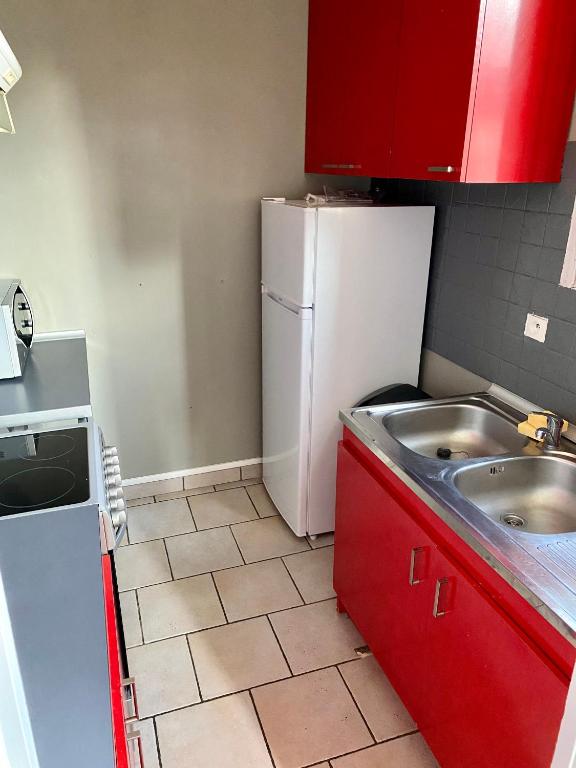 a kitchen with red cabinets and a white refrigerator at Appartement 2 pièces à Nevers in Nevers