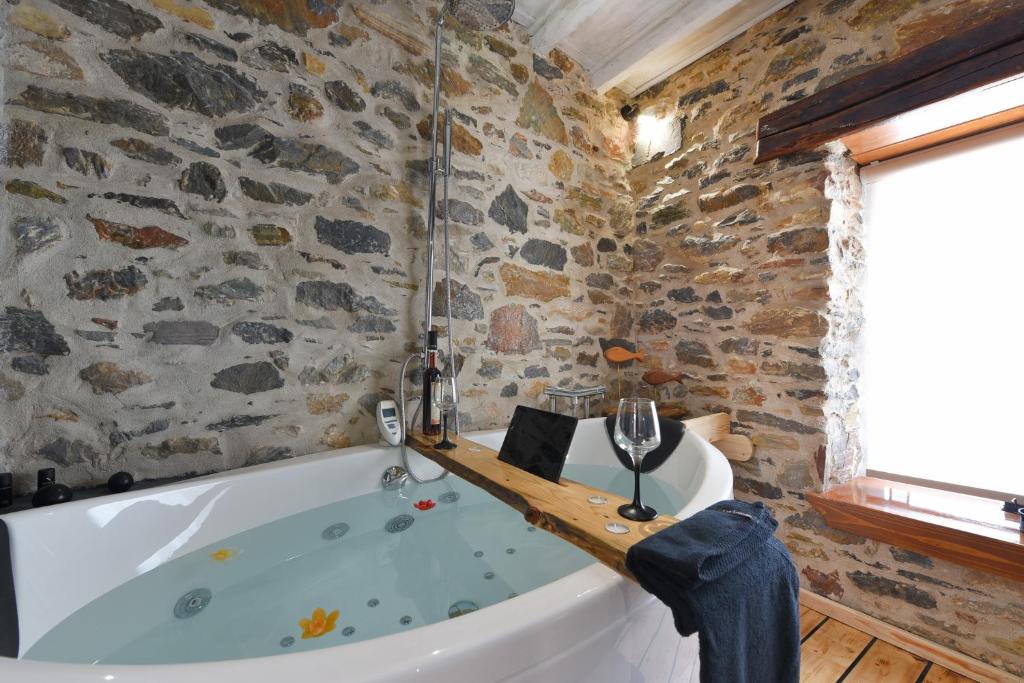 a bath tub in a room with a stone wall at Tramuntana in Ano Syros