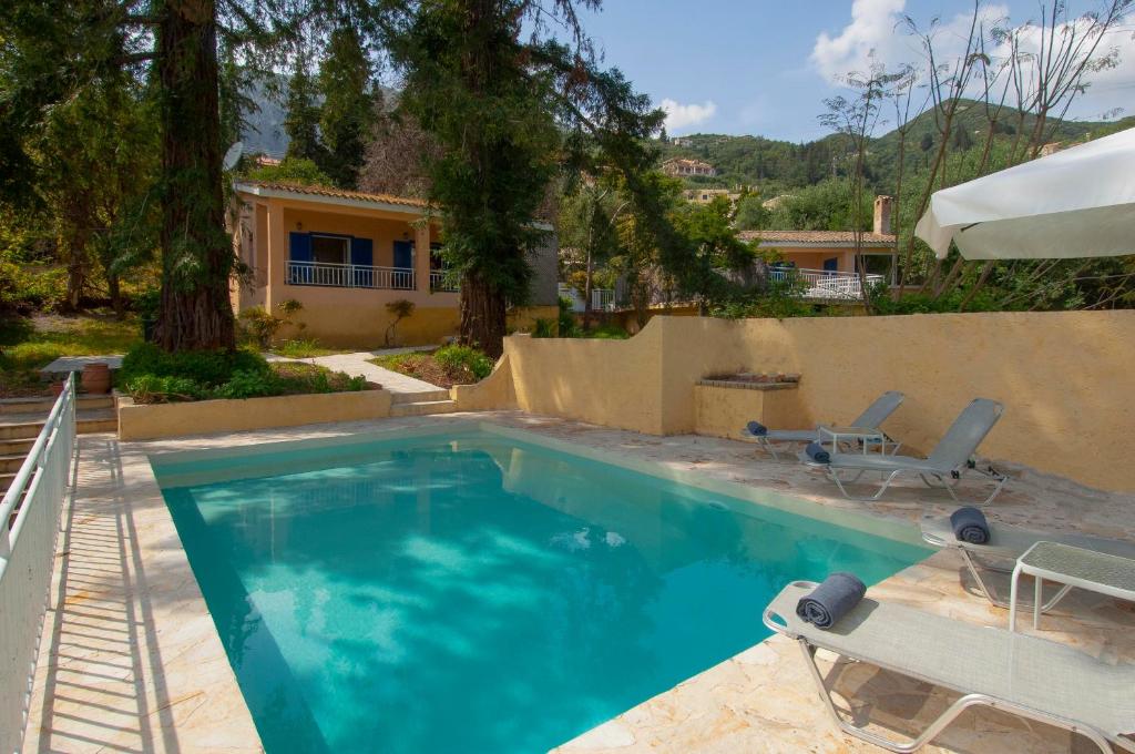 a swimming pool with two chairs and a house at Villa Serena in Nisakion