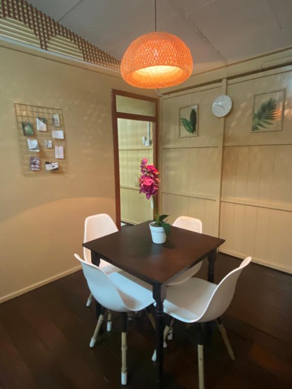 a dining room table with white chairs and a vase with flowers at ORKED LUDICIA 2 bedroom Village Cottage house in Kuala Terengganu