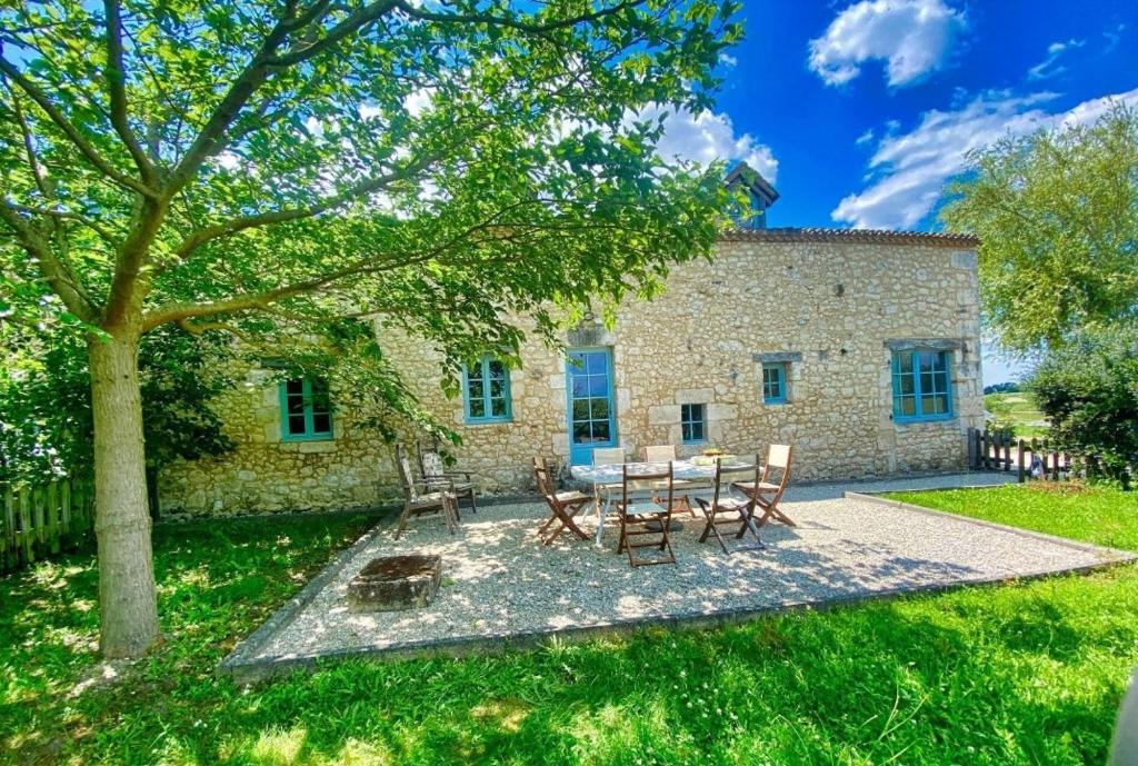 una casa de piedra con una mesa y sillas en el patio en Gite La Grange aux Oiseaux en Conne-de-Labarde