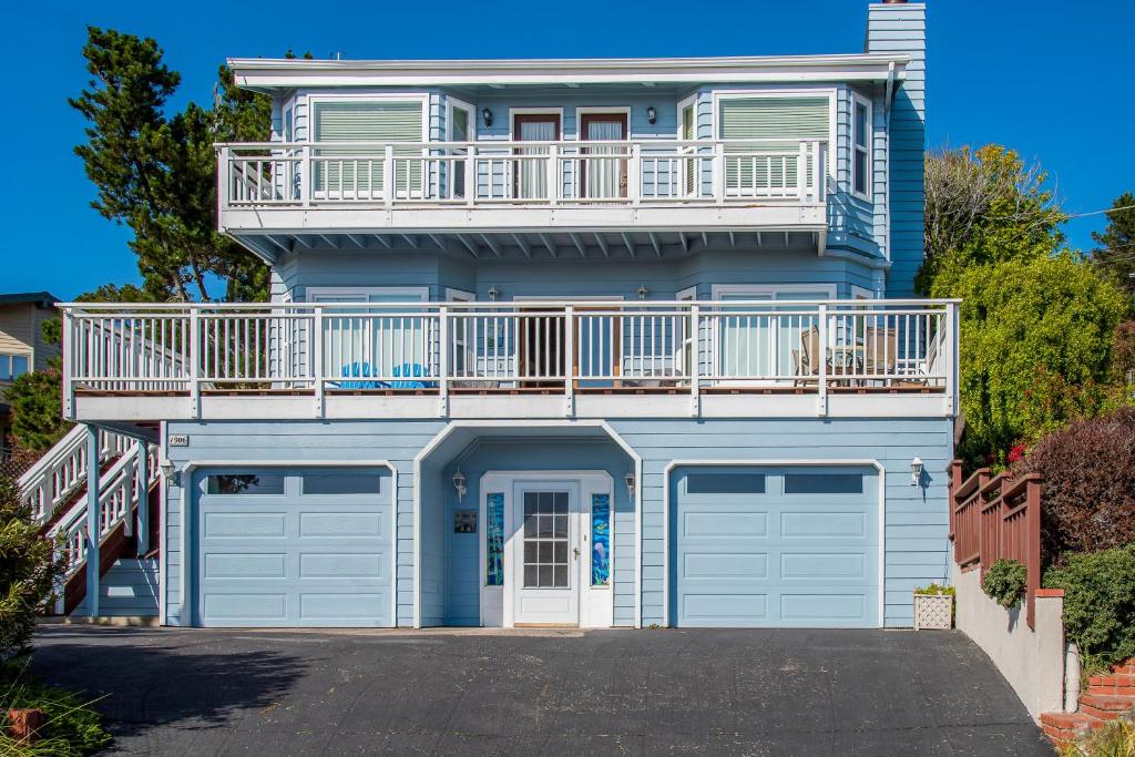 a blue house with a balcony and two garage doors at All Decked Out in Cambria in Cambria