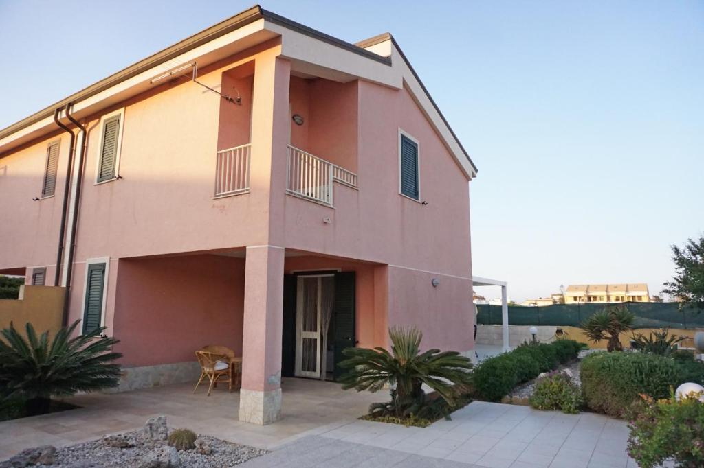 una casa rosa con una sedia davanti di Holiday House Villa AleGiù Marzamemi a Reitani