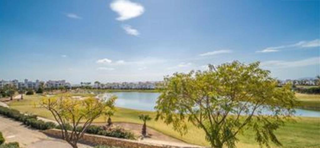 un parque con un lago y árboles en el primer plano en Bonito holiday, La Torre Golf Resort en Murcia