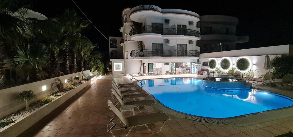 a swimming pool in front of a building at night at Elarin studios & apartments in Faliraki