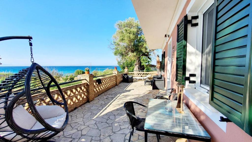 een veranda met een schommel en een tafel en stoelen bij Tonias Houses - Thea House and Vrachos Attic Appartment in Alikanas