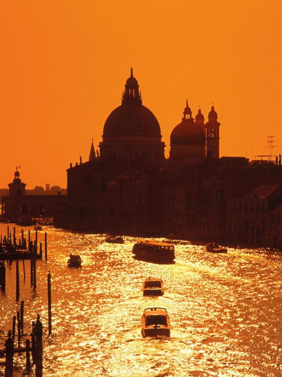 a city with boats in the water at sunset at Hotel Giudecca Venezia in Venice