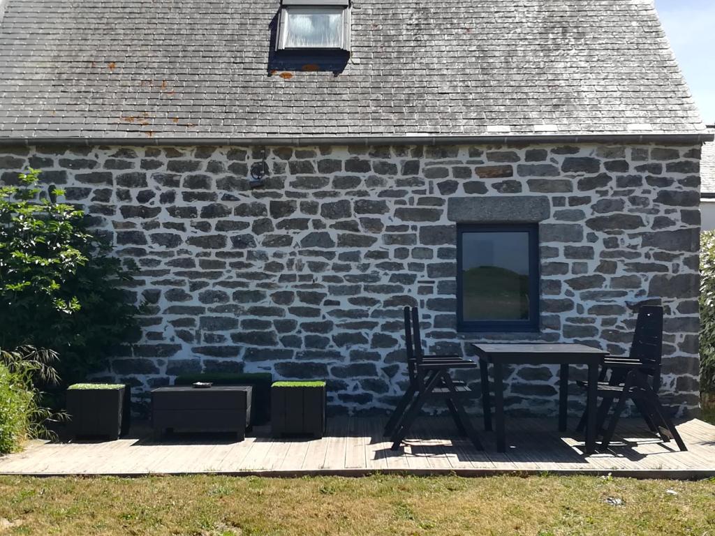 une table et des chaises devant un bâtiment en briques dans l'établissement Ty Biz, à Saint-Jean-Trolimon