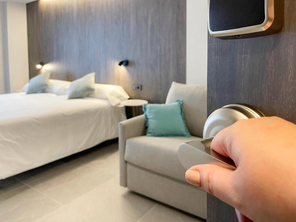 a person holding a cell phone in a hotel room at Hotel Quatre Llunes in Santa Pola
