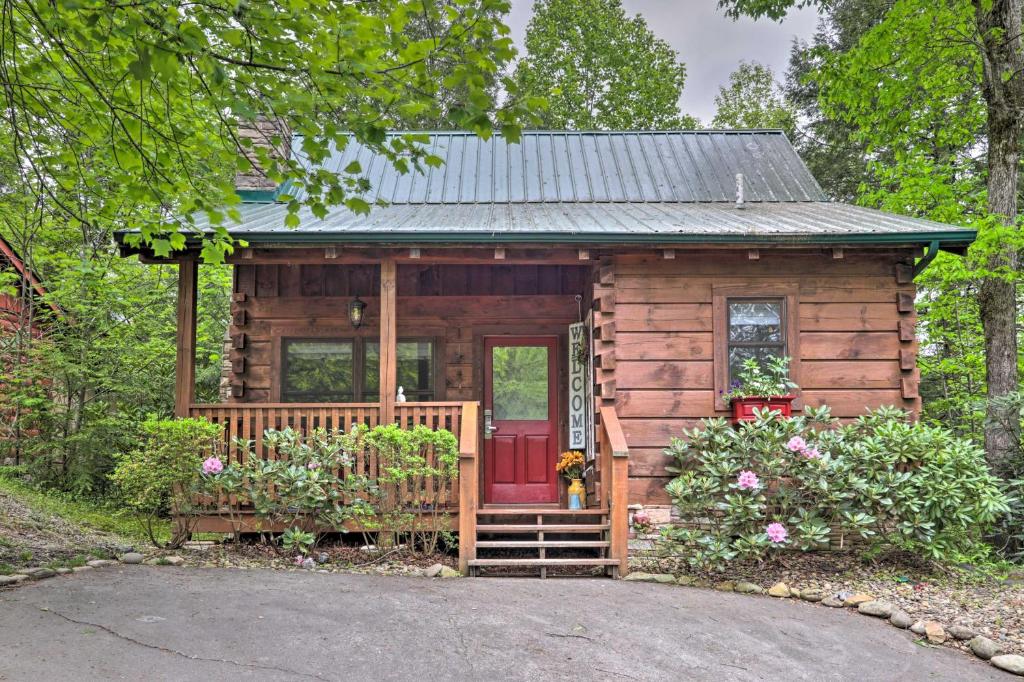 a small wooden cabin with a red door at Romantic Gatlinburg Studio Cabin with Hot Tub and Deck in Gatlinburg