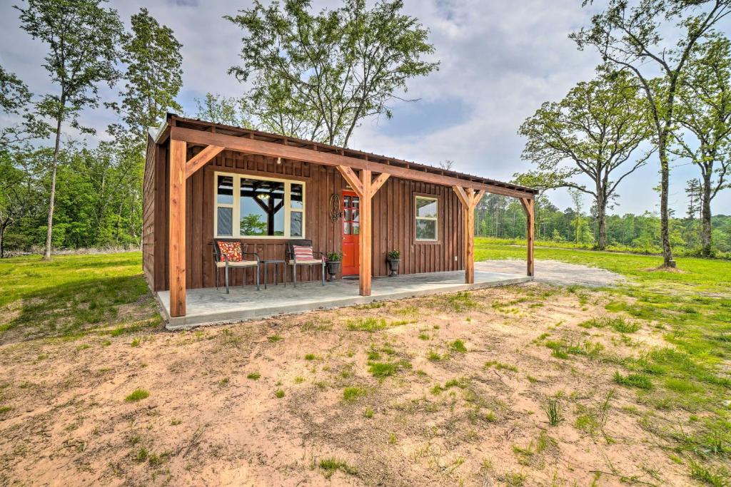 a tiny house with a porch in a field at Updated Studio Cabin in Ozark with Yard and Mtn View in Ozark