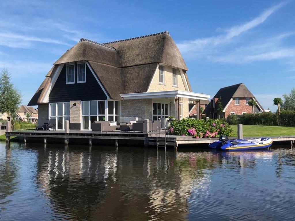 una casa en un muelle con un barco en el agua en Beautiful villa with sauna on the Tjeukemeer, en Delfstrahuizen