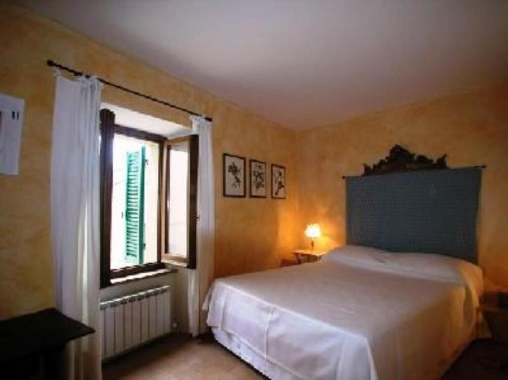 1 dormitorio con cama y ventana en La Torre di Cetona, en Cetona
