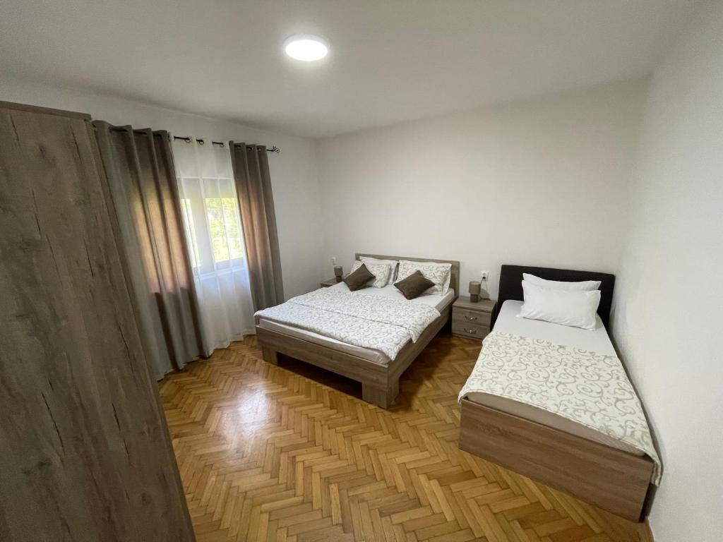 2 łóżka w pokoju z białymi ścianami i drewnianą podłogą w obiekcie Apartments Dionis w Kotorze