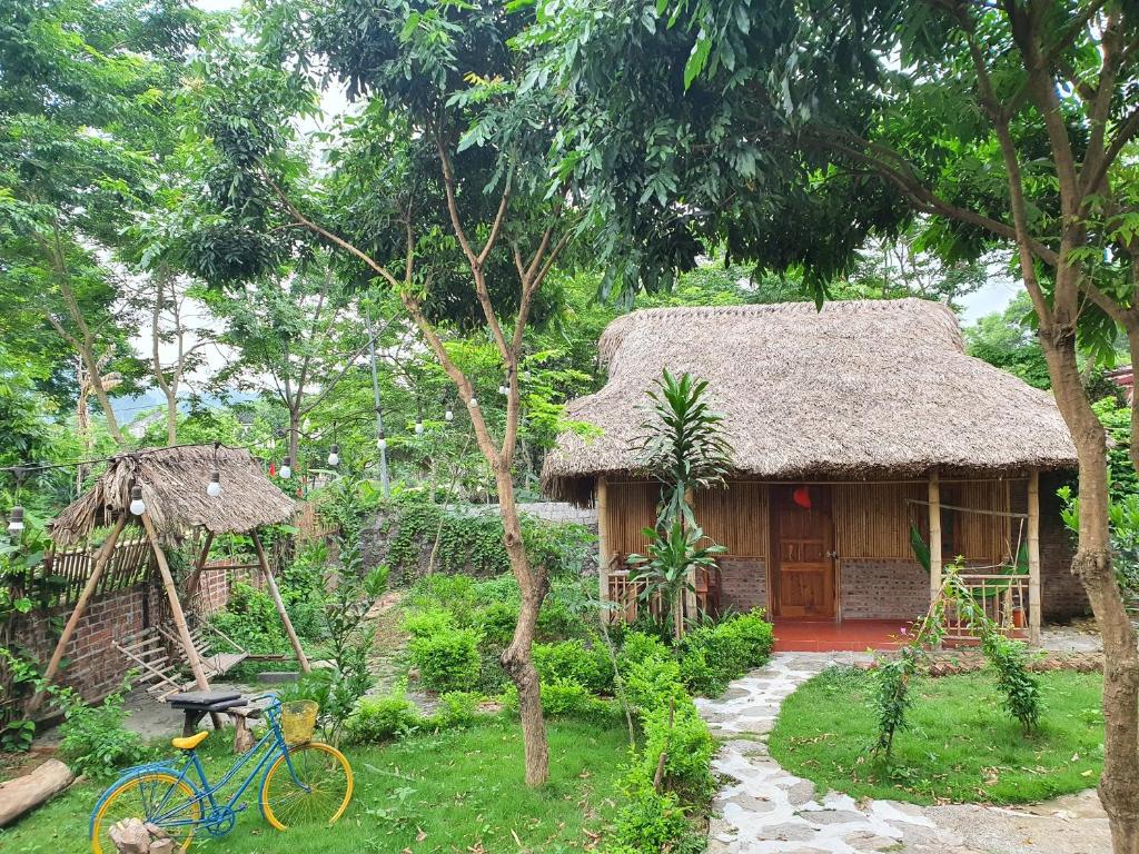 a small house with a straw roof and a bicycle in front of it at Ninh Binh Bamboo Farmstay in Ninh Binh