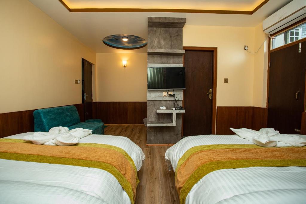 a hotel room with two beds and a chair at Gauri Shankar Hotel Nagarkot in Nagarkot