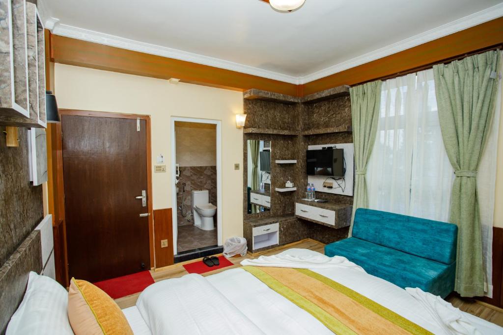 a bedroom with a large bed and a blue chair at Gauri Shankar Hotel Nagarkot in Nagarkot