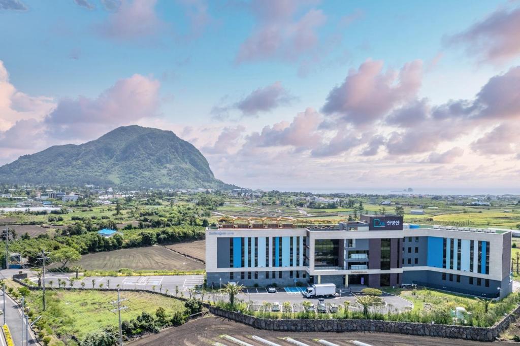 uma vista aérea de um edifício com uma montanha ao fundo em Primula Hotel - Formerly Sanbangsan Hotel em Seogwipo