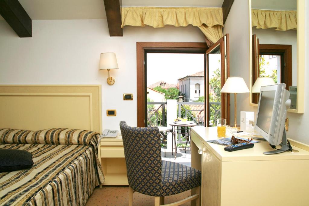 a hotel room with a bed and a desk with a computer at Hotel Giudecca Venezia in Venice