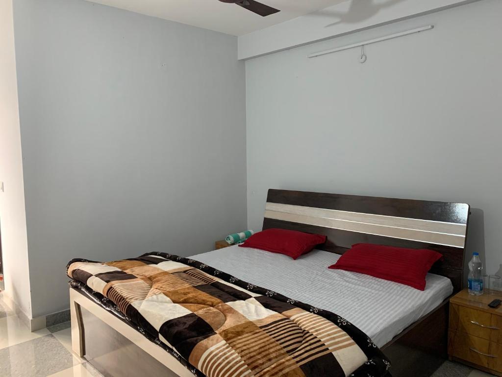 una camera con un letto con due cuscini rossi di IMBUE STAYS a Dehradun