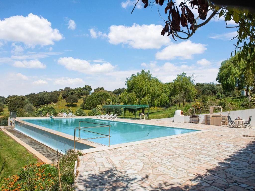 a large swimming pool in a yard with a patio at Country Farmhouse in Montemor o Novo with Swimming Pool in Montemor-o-Novo