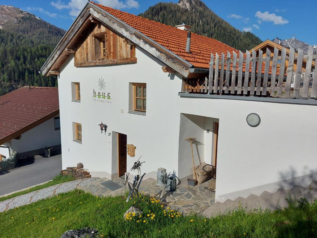 a white building with a wooden roof and a balcony at Haus Edelweiss - Ferienhaus in Spiss