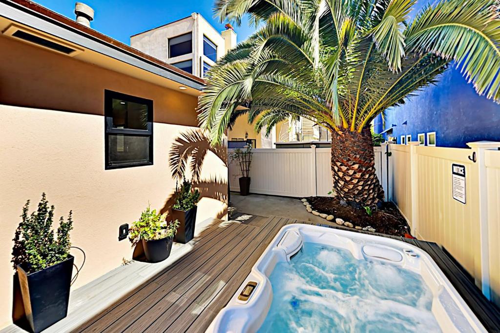 uma banheira de hidromassagem no deque de uma casa com uma palmeira em Retro Hideaway 838 em Ventura