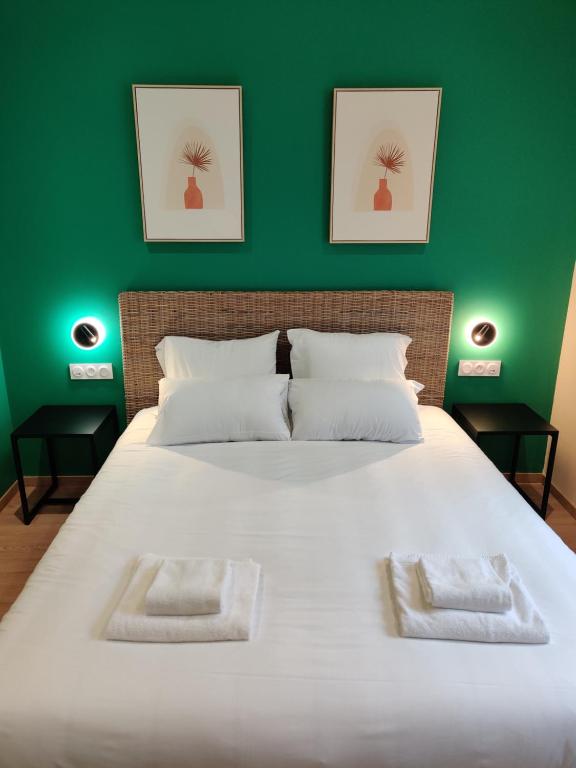 Hôtel de la Tour في لاتور-دو-بين: غرفة نوم بسرير ابيض كبير وبجدار اخضر