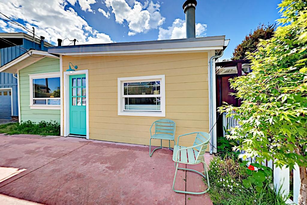 żółty dom z niebieskimi drzwiami i dwoma krzesłami w obiekcie Beach Haven w mieście Santa Cruz