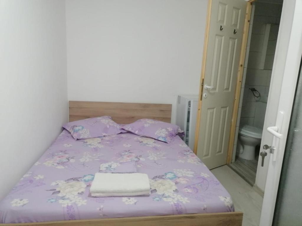 um pequeno quarto com uma cama com lençóis roxos em Emyra's holiday rooms em Constança