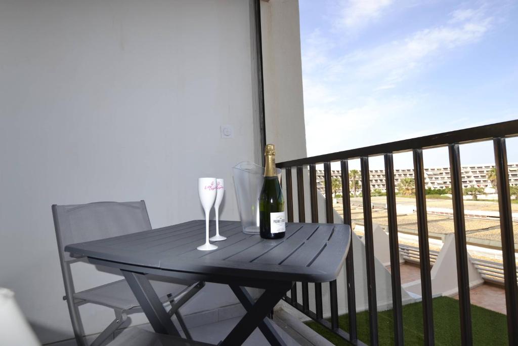 - une table avec 2 verres et une bouteille de vin sur le balcon dans l'établissement Studio Naturiste 