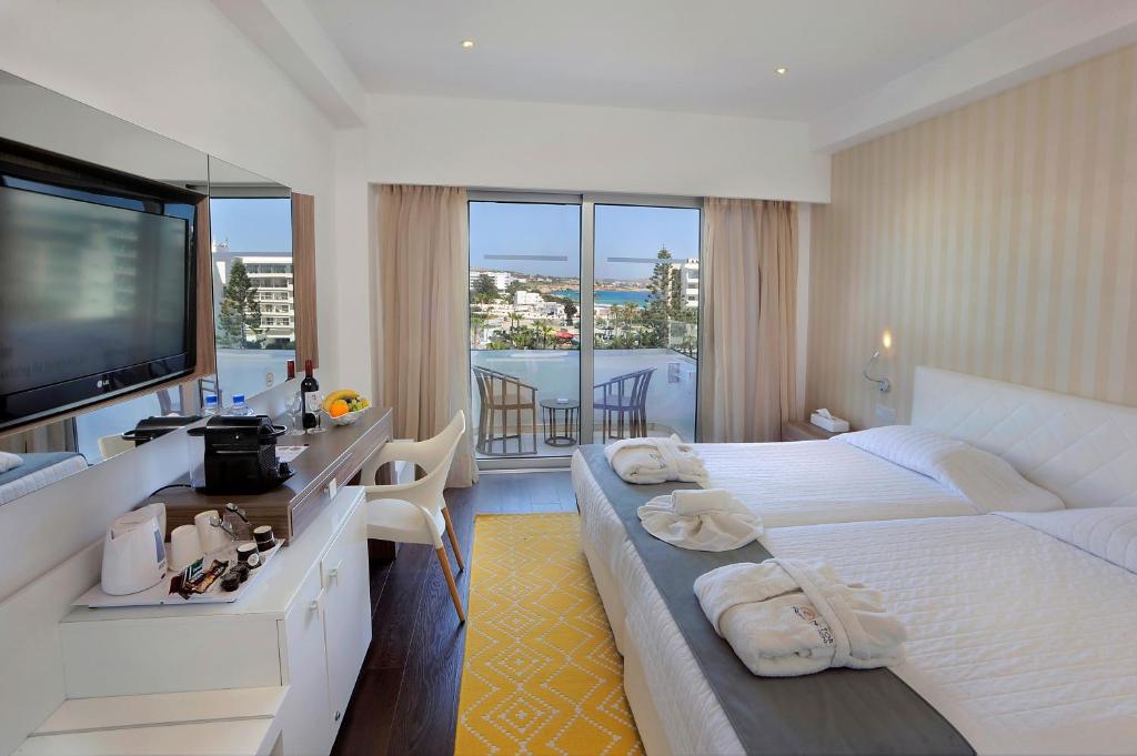 a hotel room with two beds and a flat screen tv at Nestor Hotel in Ayia Napa