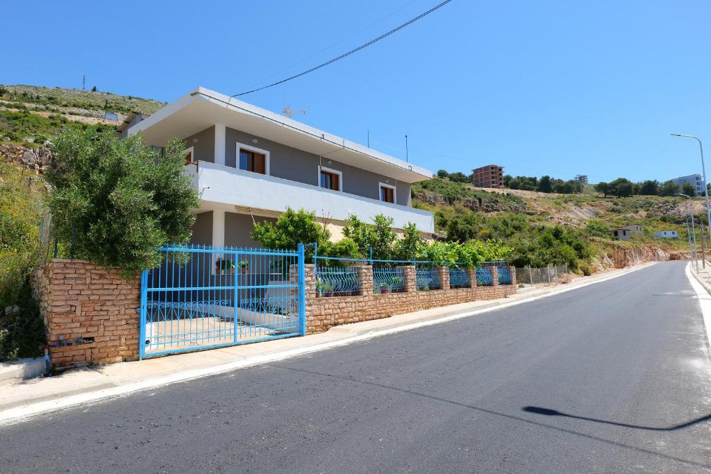 een huis met een blauw hek aan de kant van een weg bij Villa Seventh Heaven in Sarandë