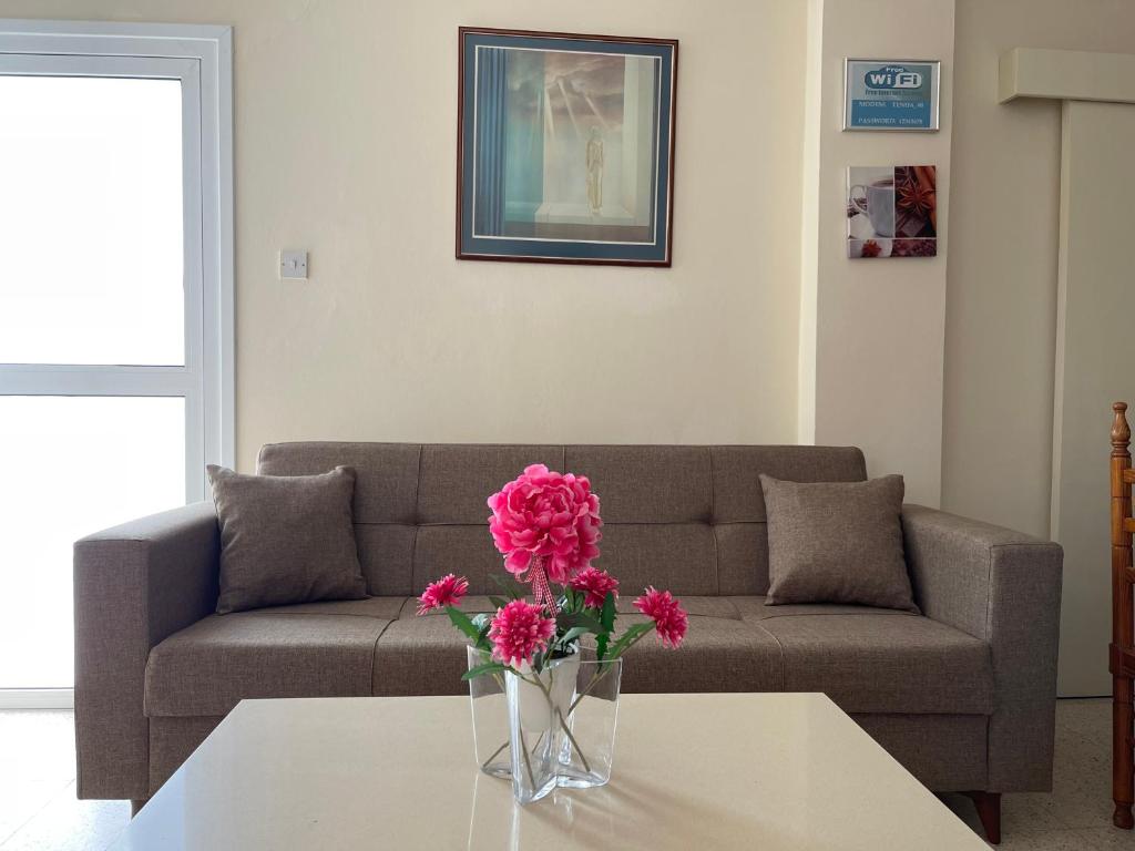 una sala de estar con sofá y un jarrón con flores sobre una mesa en Terpsithea Apartments, en Ayia Napa