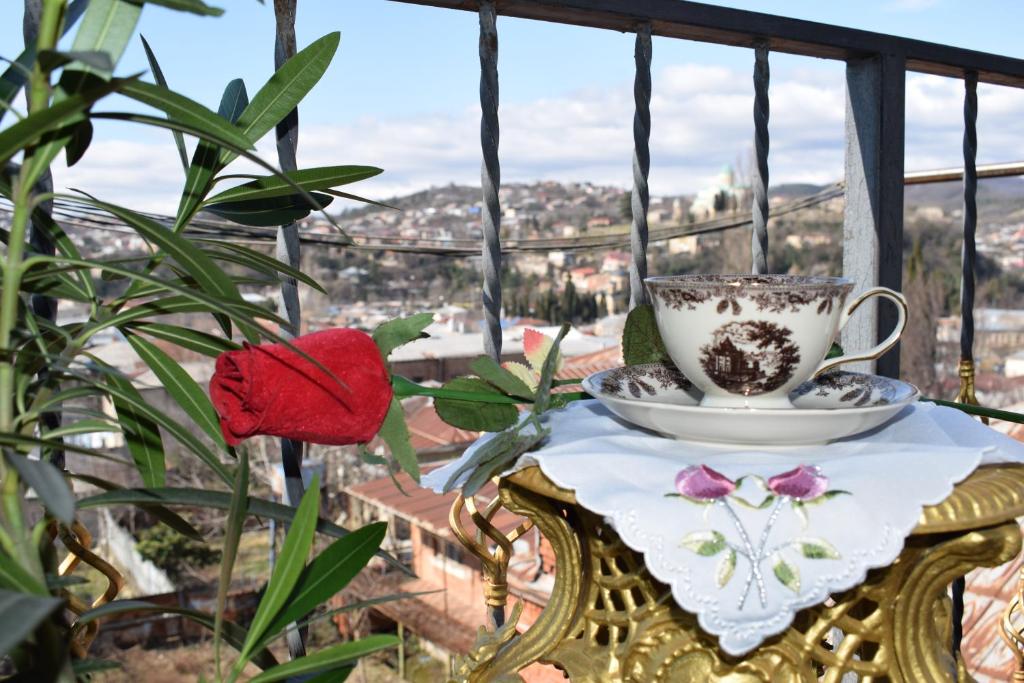 a tea cup and saucer on a table on a balcony at Excellent Hostel Kutaisi in Kutaisi