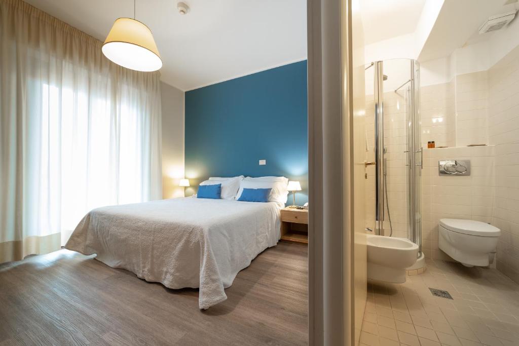 a bedroom with a bed and a shower and a toilet at Hotel La Vela in Passignano sul Trasimeno