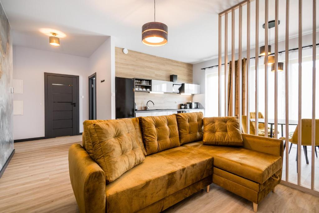 a living room with a brown couch and a kitchen at Rakowicka Old Town Luxury Apartments WAWELOFTS in Krakow