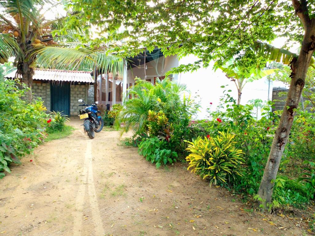 a person riding a motorcycle down a dirt road at U new guest house in Nilaveli